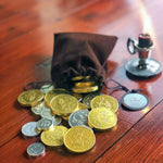 Load image into Gallery viewer, A pouch of loot fit for an adventure!   150g of white chocolate (silver) and milk chocolate (gold) coins fill this velvet drawstring bag - perfect for the swashbuckler or heroic outlaw in your life! Who doesn&#39;t love chocolate coins? Now you can take them with you - just make sure you leave enough to pay any tolls or taverns along your way! 
