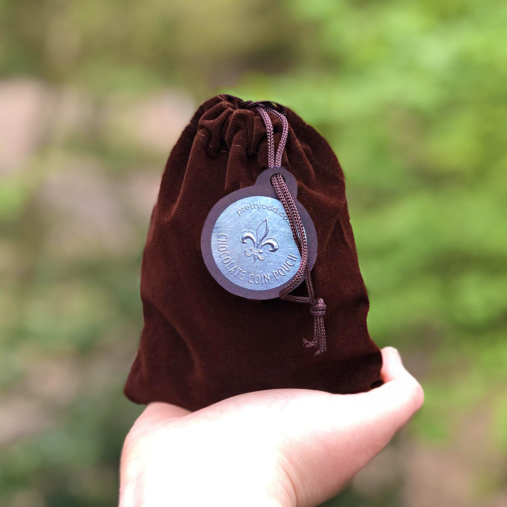 A pouch of loot fit for an adventure!   150g of white chocolate (silver) and milk chocolate (gold) coins fill this velvet drawstring bag - perfect for the swashbuckler or heroic outlaw in your life! Who doesn't love chocolate coins? Now you can take them with you - just make sure you leave enough to pay any tolls or taverns along your way! 